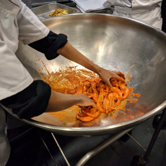 Cooked shrimp being tossed with Scotch Bonnet Pepper Sauce